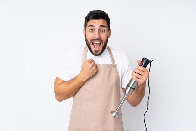 Man using hand blender on white wall celebrating a victory