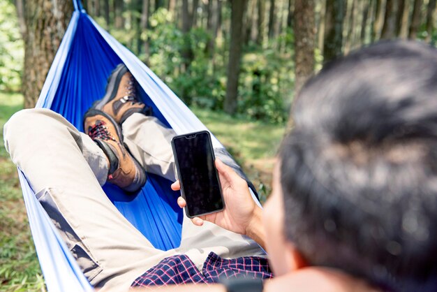 Man using his mobile phone while relaxing in hammock