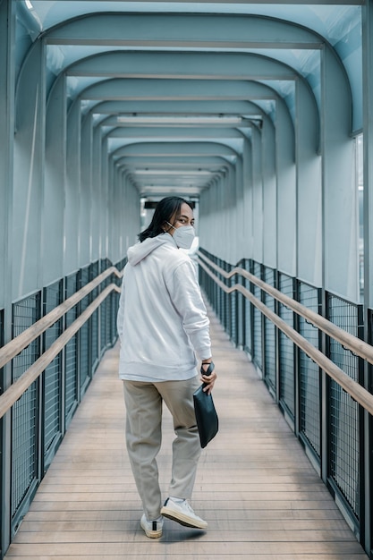 man using hoodie walking on pedestrian bridge