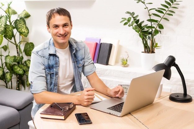 Man Using Laptop On Desk At Home