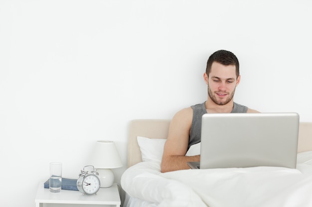 Man using a laptop in his bedroom