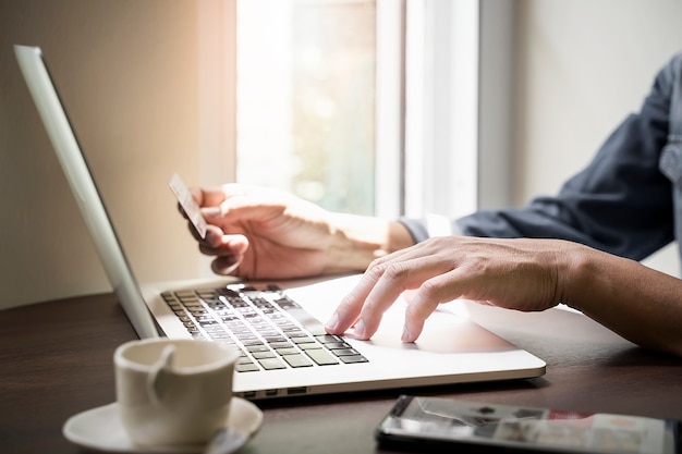 Man using laptop and holding credit card to buying online at home