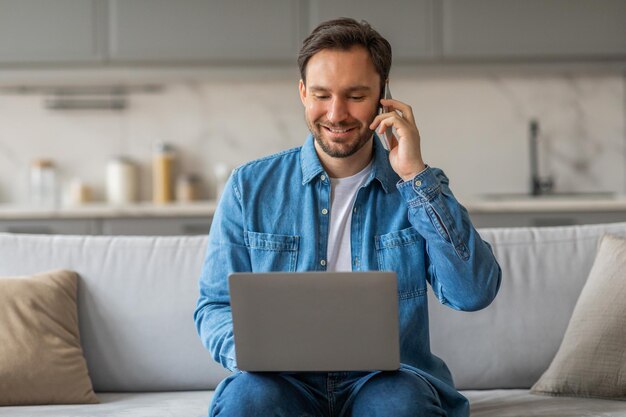 Photo man using laptop and phone while sitting on a couch