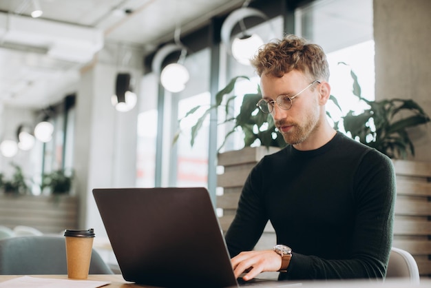 Man using laptop sitting at conference table in office