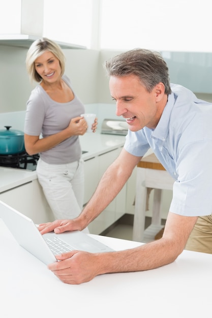 Man using laptop with woman in the kitchen