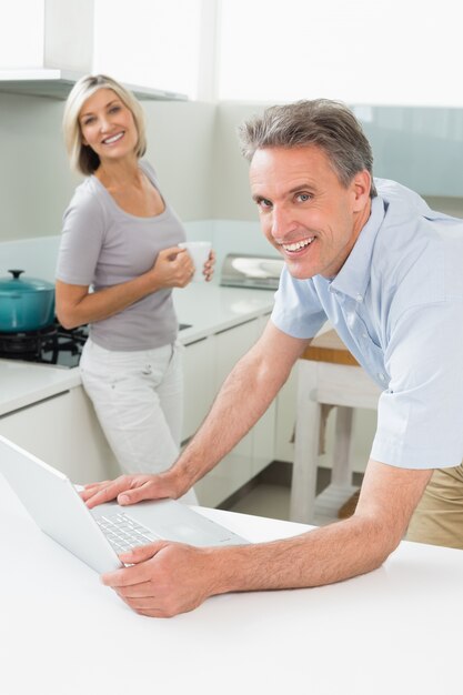 Man using laptop with woman in the kitchen