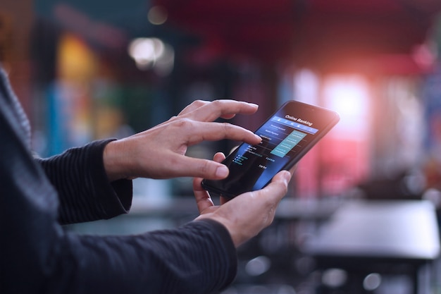 Man using mobile smartphone for online banking in cafeteria.