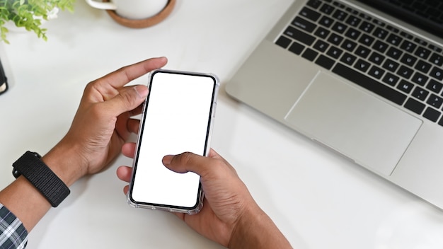 Man using mockup mobile phone on office desk with clipping path display.