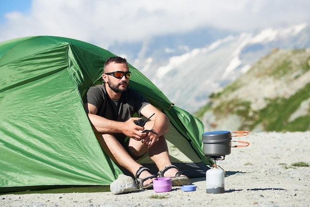 Man using radio near tent in mountains