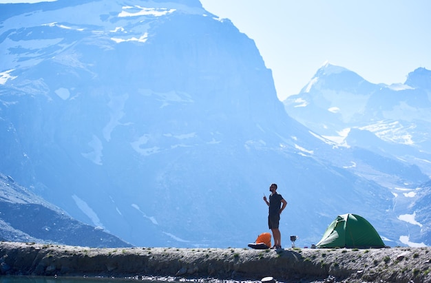 Man using radio near tent in mountains