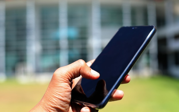 A man using smartphone in front of the office building.