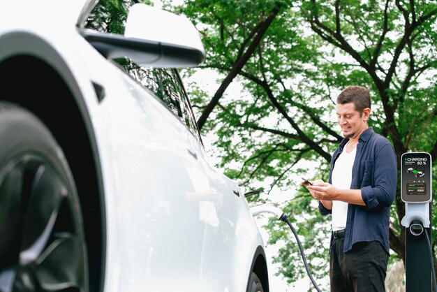 Photo man using smartphone to pay for electric car charging exalt