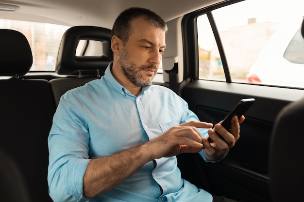 Man using smartphone sitting in passenger seat of car