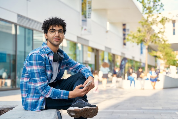 Man using smartphone while sitting at the city street alone