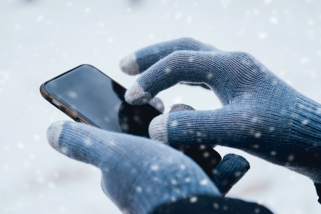 Man using smartphone in winter with gloves for touch screens