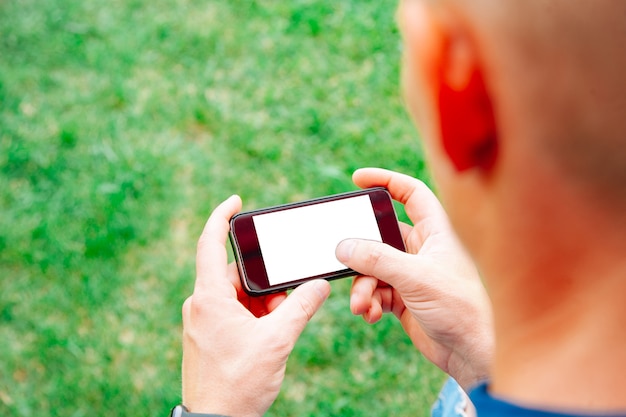 Man using smartphone with blank screen outdoors, closeup. Mock up for design