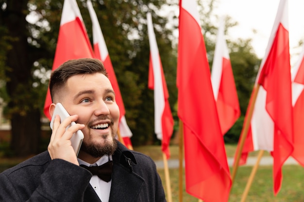 Man using smartphone with flags of Poland behind