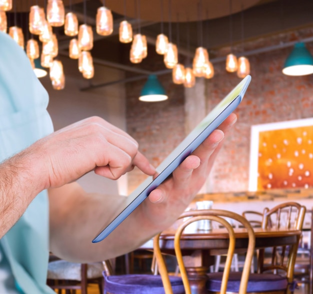 Photo man using tablet pc against coffee shop with tables and chairs