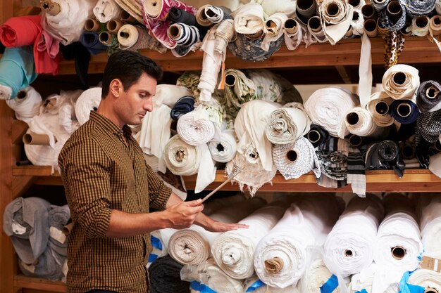 Man using tablet selects fabric from storage shelves