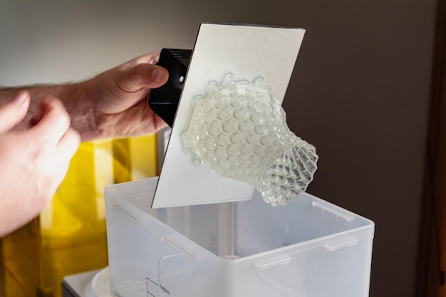 Man using a wash machine to clean a transparent 3d resin object