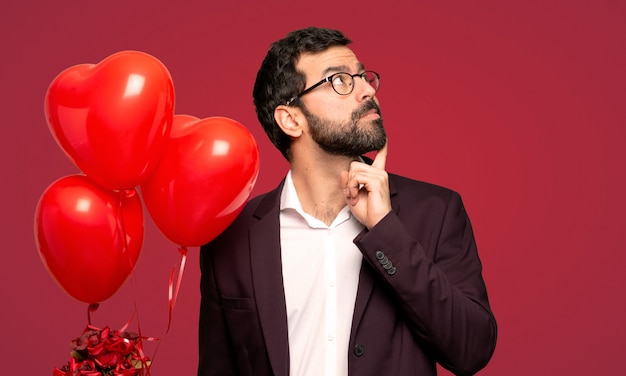 Man in valentine day thinking an idea while looking up over red background