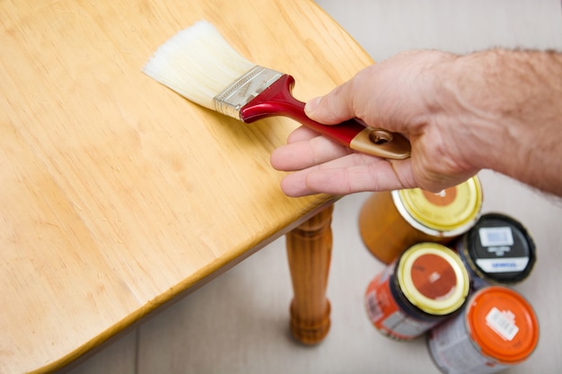 Man varnishing a chair with paintbrush