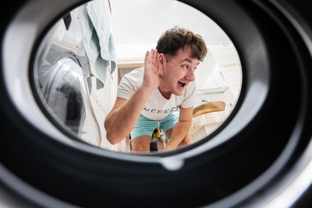 Man view from washing machine inside Male does laundry daily routine Listens to the sound inside