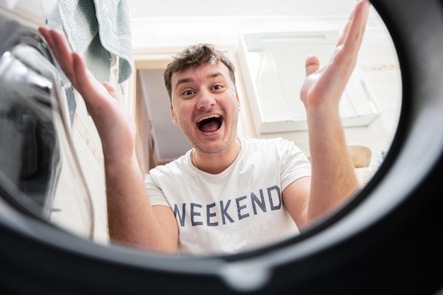 Man view from washing machine inside Male does laundry daily routine Satisfied expression on his face spreading hands to the side