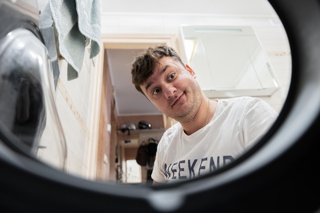 Man view from washing machine inside Male does laundry daily routine Surprised facial expression