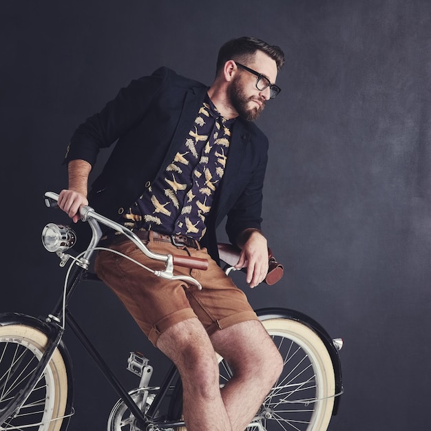 Photo man vintage and bicycle in studio with fashion for eco travel transport and trendy style with glasses cyclist relaxed and weekend isolated on dark background with casual wear clothing and cool