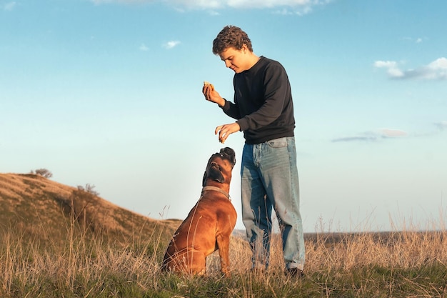 a man on a walk eats a hamburger himself and feeds his dog a treat