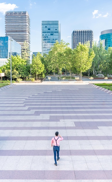 Man walking along an urban square and skyscrapers in background