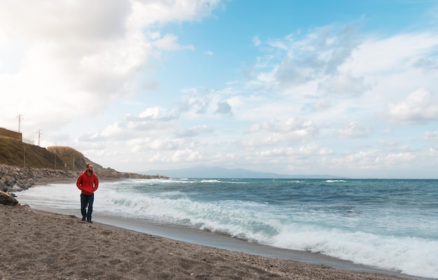 Man walking on a beautiful cloudy day on a beach with churning water