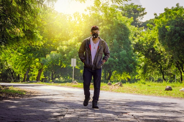 Man walking in desolate street, man walking head-on in lonely street, young man with mask walking down the street