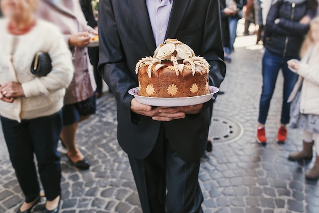 Man walking and holding traditional ukrainian wedding cake with roses delicious brown bread