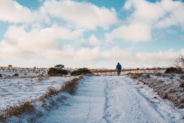 Man walking in the middle of the field on a snowy road