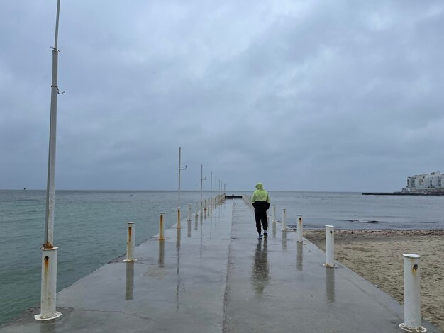 Man walking in the rain on a pier at the beach