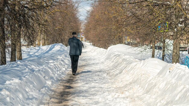 A man walks down a snow - covered street with a sign that says'snow'on it