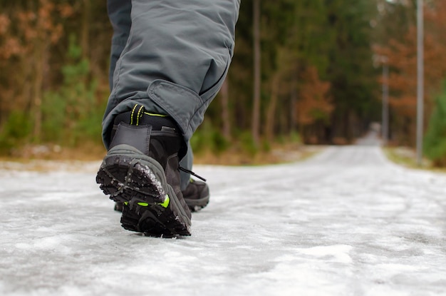 A man walks on a slippery road, the first snow in the park, winter shoes, the road is covered with slippery ice. Dangerous. Close-up