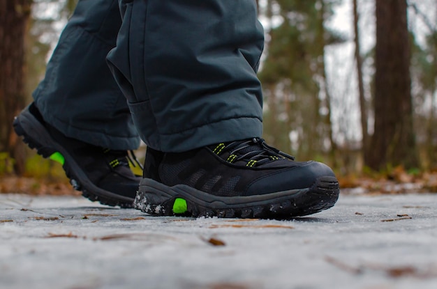 A man walks on a slippery road, the first snow in the park, winter shoes, the road is covered with slippery ice. Dangerous. Close-up