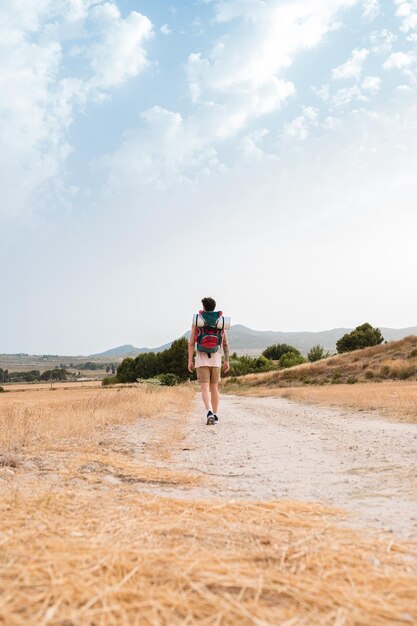 Man walks with a backpack of a hiker through a mountainous landscape