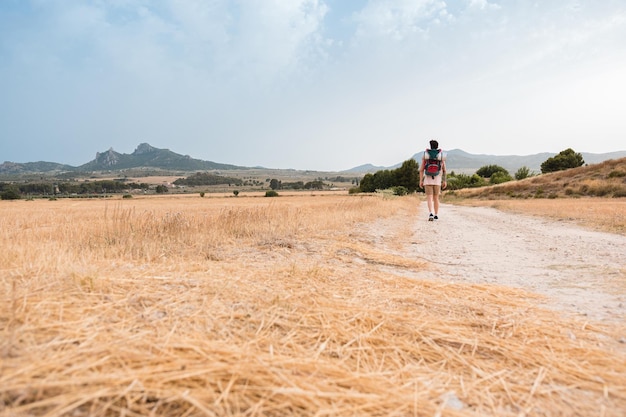 Man walks with a backpack of a hiker through a mountainous landscape