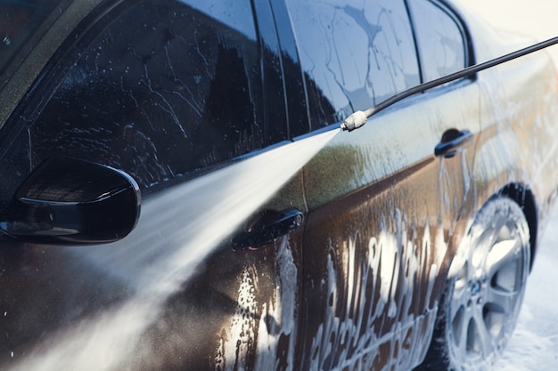 A man washes his car with water