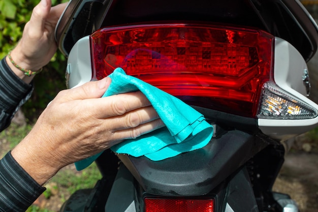 A man washes a motorbike with a rag Maintenance and care of motor vehicles