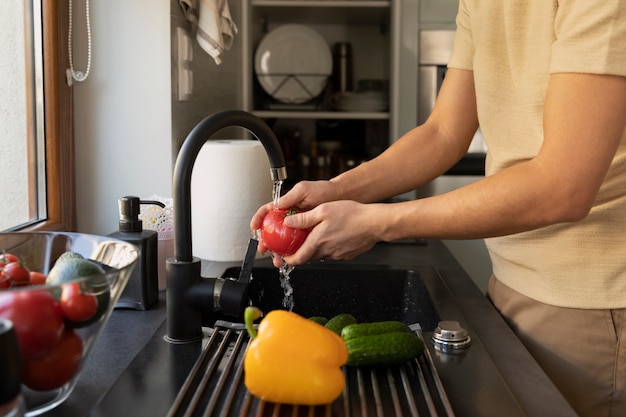 Man washes vegetables in the kitchen sink