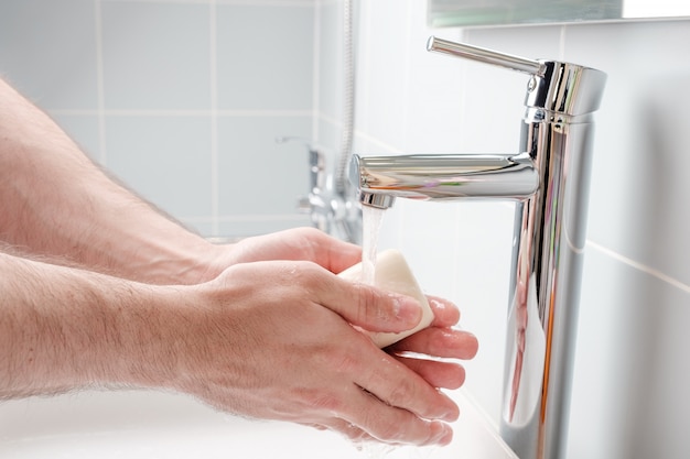 Man washing hands with soap in the bathroom