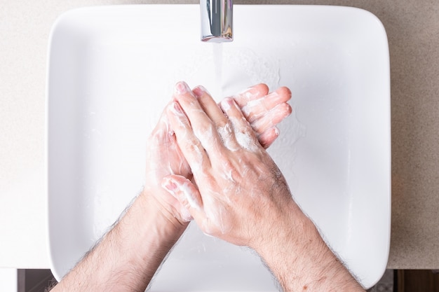 Man washing hands with soap in the bathroom