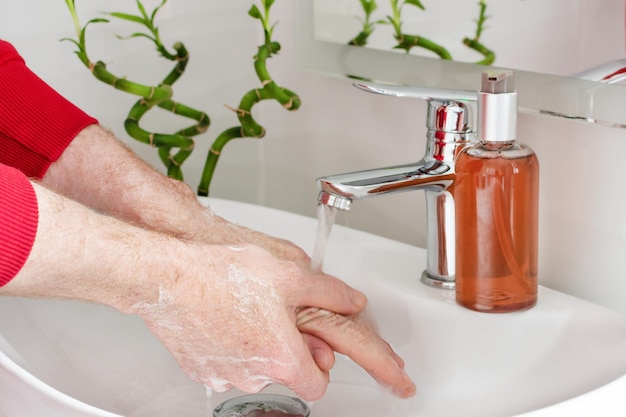 Man washing hands with soap in modern bathroom sink Virus prevention by washing hands frequently