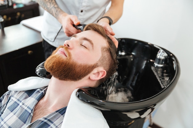 Man washing head to client in barbershop