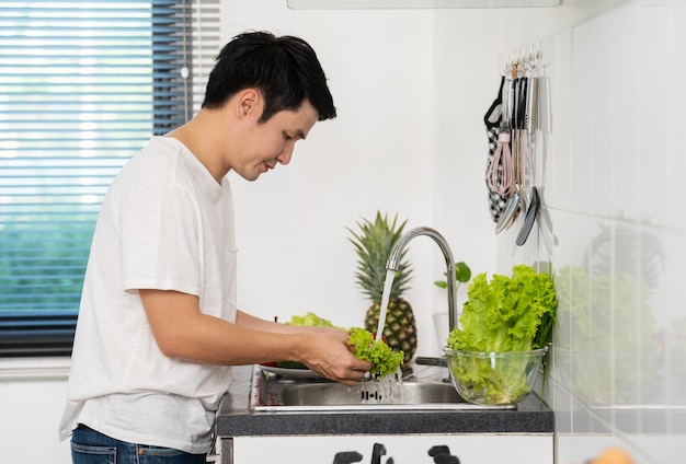 Man washing vegetables in the sink in the kitchen at home